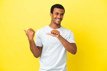 African American handsome man on isolated yellow background pointing to the side to present a...