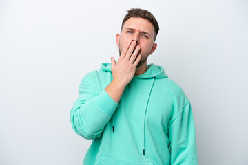 Young caucasian man isolated on white background yawning and covering wide open mouth with hand