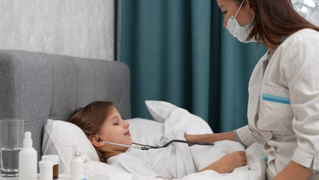 Pediatrician woman with stethoscope checking little patient girl at home