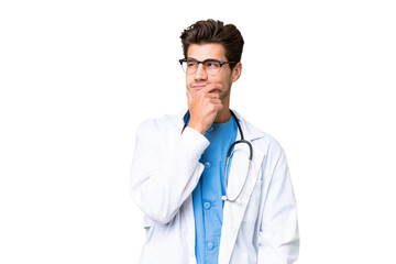 Young doctor man over isolated background having doubts and with confuse face expression