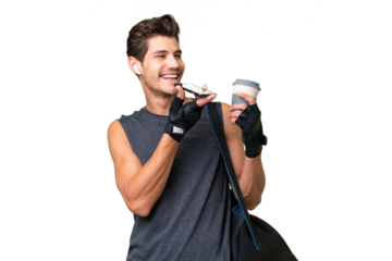 Young sport caucasian man with sport bag over over isolated background holding coffee to take away and a mobile