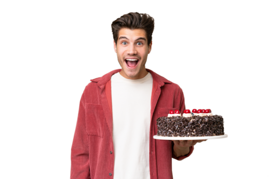 Young caucasian man holding birthday cake over isolated background with surprise facial expression