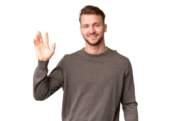 Young handsome caucasian man over isolated chroma key background saluting with hand with happy expression