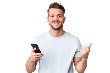 Young handsome caucasian man over isolated chroma key background using mobile phone while doing...