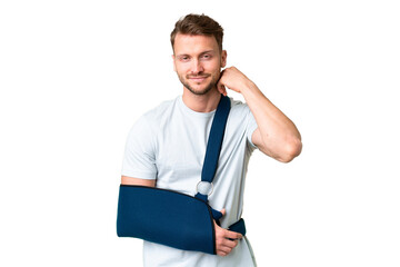 Young caucasian man with broken arm and wearing a sling over isolated chroma key background laughing