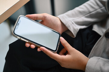Closeup young woman hands holding mobile phone with white blank screen