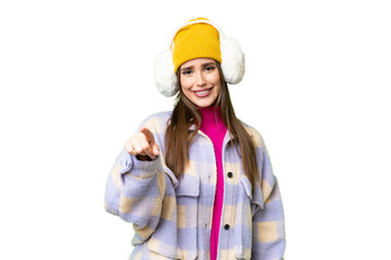 Young woman wearing winter muffs over isolated chroma key background points finger at you with a...