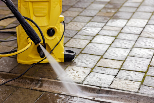 Washing Service of Pavement Paving Stones. High Pressure Cleaning Street Road. Clean Concrete Gutter on Floor of Garden with Karcher.