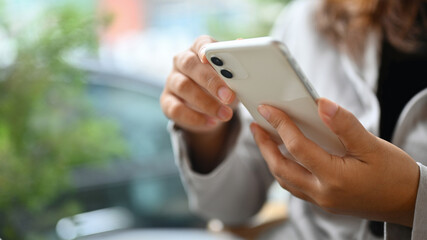 Young woman using mobile phone typing messages or communicating in social network
