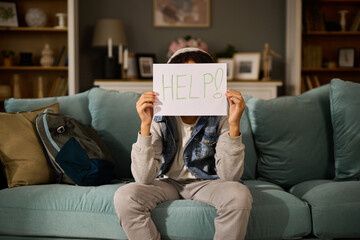 Teenage boy holding paper card with word Help