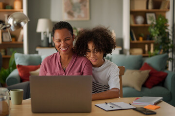 Mother and teenage son using a laptop at home