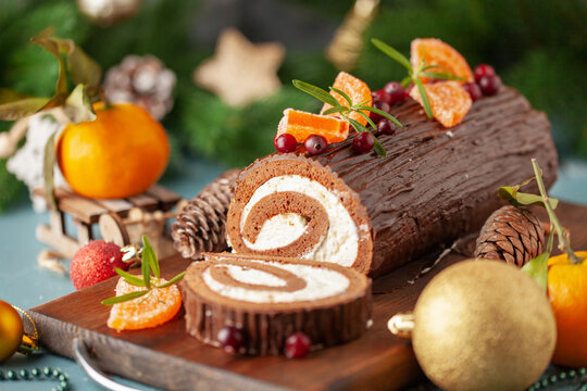 Yule log roll cake with chocolate ganache  on Christmas decorated background