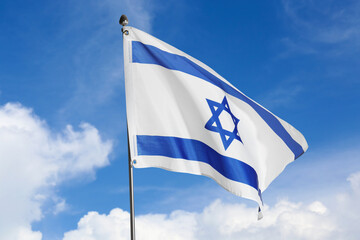 National flag of Israel against blue sky with clouds
