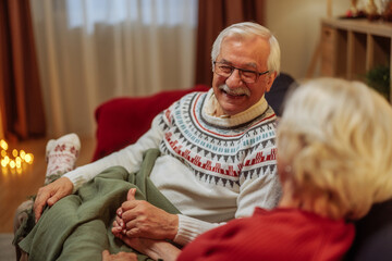 Older couple sitting on a sofa, talking and laughing during Christmas holidays