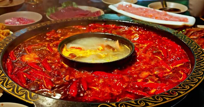 Chinese spicy hot pot cuisine. A layer of red chili pepper floats in the boiling hot pot base. Famous Chongqing Spicy Hot Pot, China.