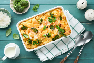 Pasta Broccoli casserole. Baked Mac and cheese with broccoli, cream sauce and parmesan on old rustic wooden background. Healthy or baby food. American Casserole Top view. Copy space.