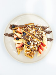 Belgian waffles with chocolate, berries and nuts. Close-up on a white background.