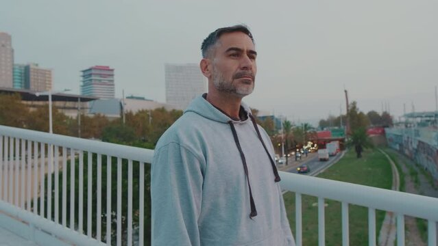 Middle-aged man in sportswear walks along bridge