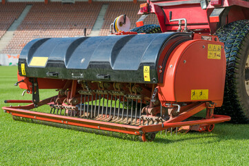The tractor with aerator machine during aerating a soccer field.
