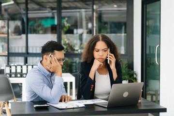 Furious two Asian businesspeople arguing strongly after making a mistake at work in office.