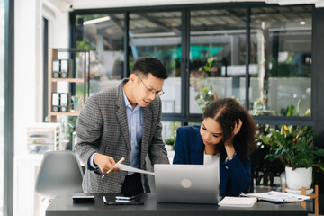 Furious two Asian businesspeople arguing strongly after making a mistake at work in office.