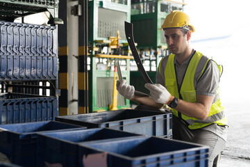 Storage warehouse and manufacturing concept. Male warehouse worker working with laptop computer and inspecting quality for auto spare parts at warehouse