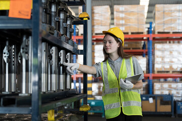 Warehouse and manufacturing concept. Female warehouse worker working with tablet and inspecting...
