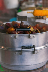 The old and worn, stainless steel pot steaming the japanese sweet potatoes.
