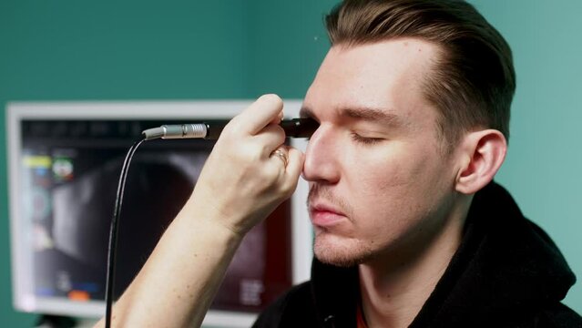 In a modern clinic, an ophthalmologist performs an eye ultrasound (B-scan) for an in-depth examination of the eyes of a young man. The concept of modern technologies for vision diagnostics.
