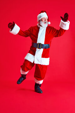 Happy and cheerful mature man looks like Santa Claus with long grey bear dancing because magical winter holidays start. Concept of Merry Christmas.