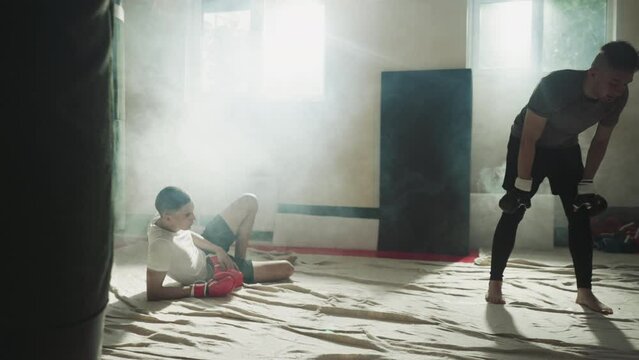 Fatigued male boxers pausing after intense boxing session. Weariness from physical exertion. Fatigue and excess energy after intensive work on body in gym