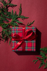 Christmas concept composition with tartan pattern gift box on the red background. Winter holiday...