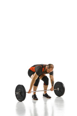 Young muscular strong man, weightlifter training, lifting heavy weights against white background