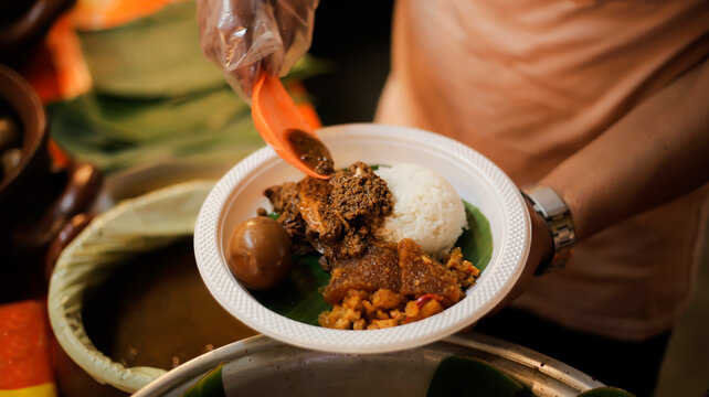 A man serves customers gudeg rice and side dishes, a typical Yogyakarta gudeg food