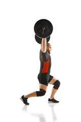 Side view. Muscular, athletic man, weightlifter training, lifting heavy barbell against white...