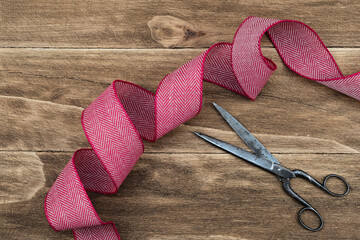 Red and white ribbon and antique scissors on wooden background. Christmas rustic and natural background. Banner. Top view.
