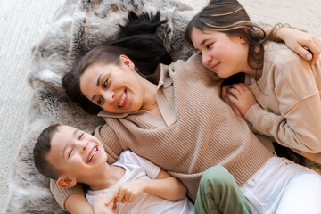 Mom and kids lying on bed in decorated bedroom and laughing concept winter