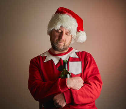 Man dressed as Santa Claus who has fell asleep holding a bottle of wine.