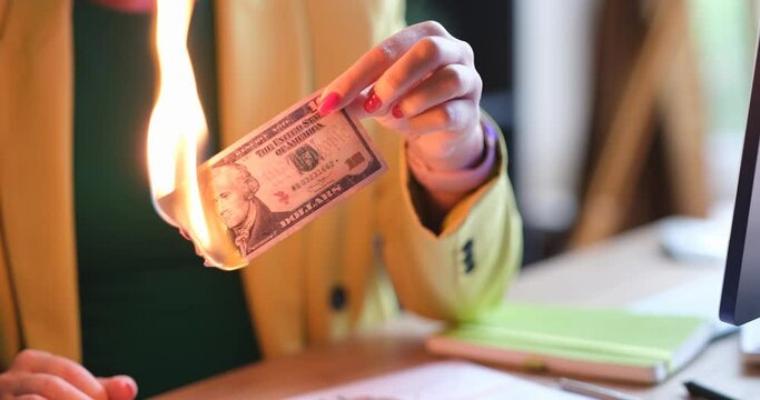 Woman sets fire to ten dollar bill with match. Burning money concept