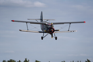 Fototapeta na wymiar AIRPLANE - A biplane approaches to land at a field airport