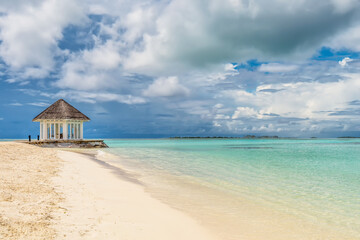 Scenic view of beach hut in Maldives with turquoise water and dramatic sky