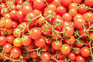 Red ripe cherry tomatoes closeup on the farm market stall. Food background.