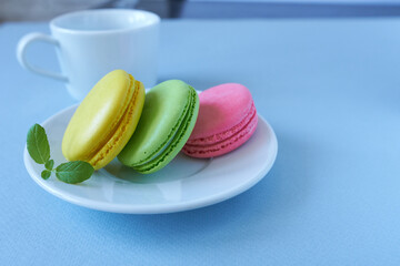 Colorful macaroons in a white plate on a blue background