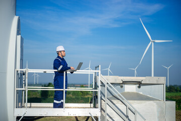 A maintenance engineer is checking the operation of a wind turbine with his laptop.