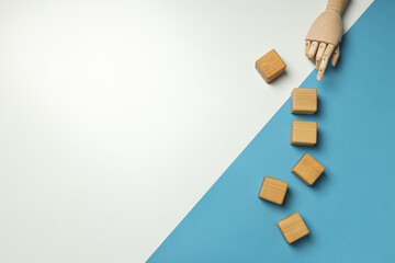 Wooden cubes and hand on white and blue background, space for text