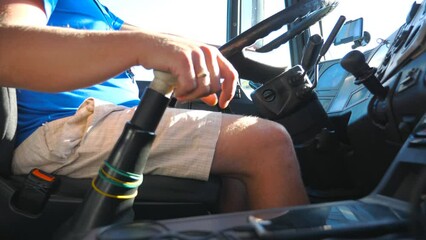 Low view of unrecognizable driver sitting behind steering wheel of his truck and riding on country road. Man controlling his truck driving to destination at sunny day. Inside shot Slow motion Close up