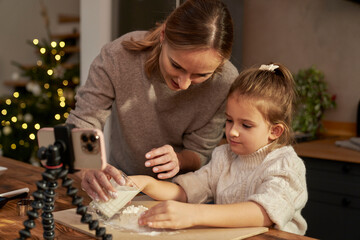 Mother and daughter taking recipe for gingerbread cookies from the mobile phone