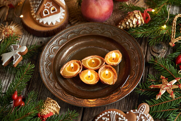 Obraz na płótnie Canvas Christmas candles made of beeswax floating in water, with gingerbread house