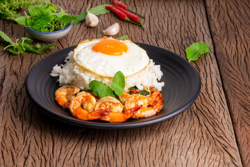 Stir-fried shrimp with basil and eggs Thai street food arranged on black plates Spicy Thai food placed on a wooden table. Top view.