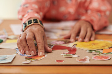 Fototapeta premium Closeup image of creative woman glueing cut photos of flowers on cardboard piece